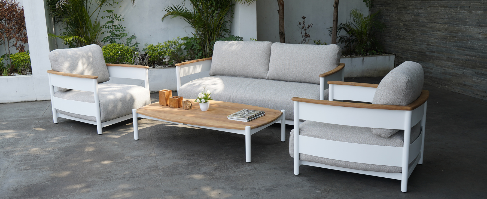 white framed lounge with teak arms on a stone floor patio