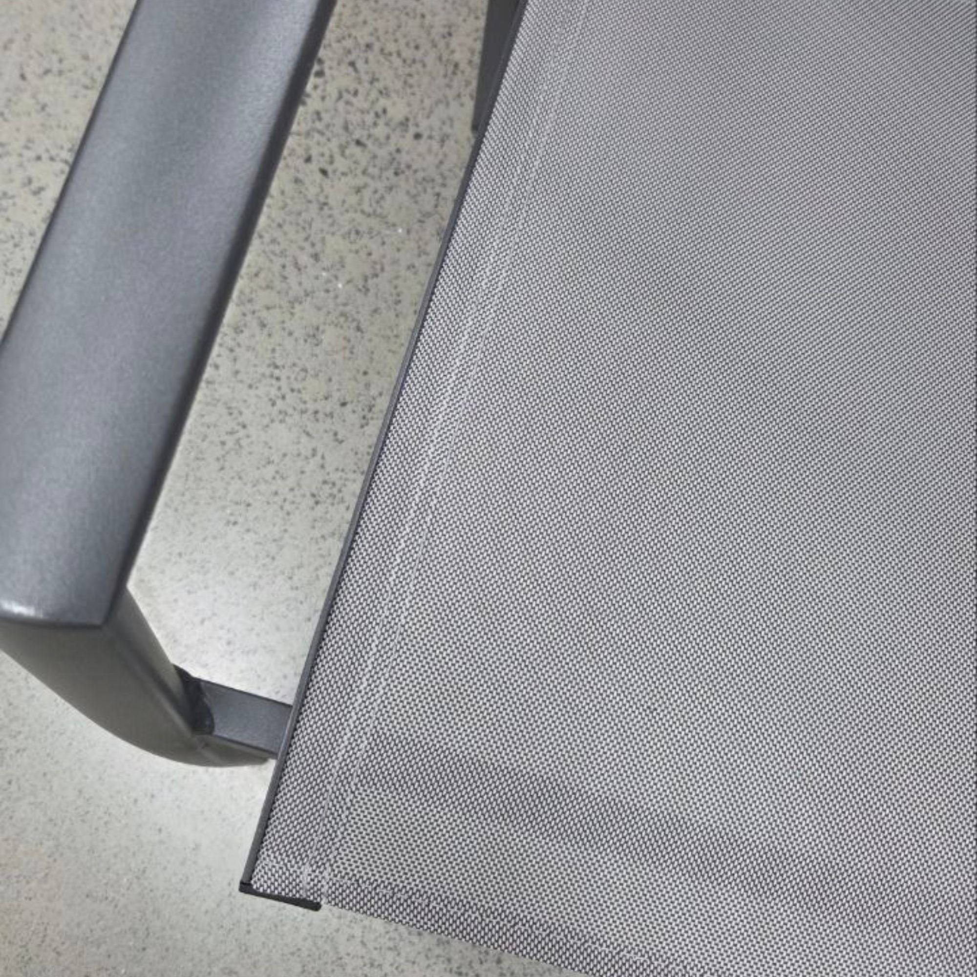 Close-up of a gray mesh screen on a chair armrest.