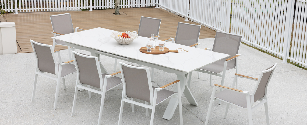 white extendable dining setting, outdoors on a white tiled patio, 10 chairs and decor on top