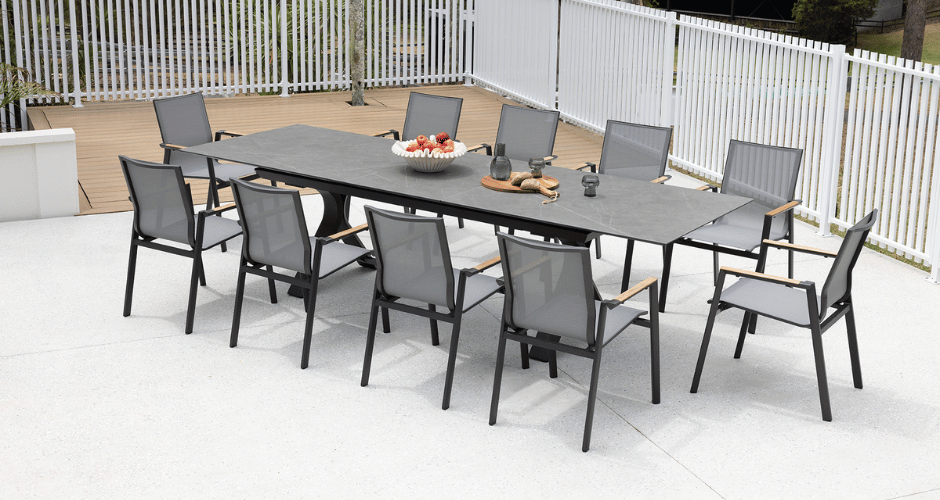 charcoal extendable dining setting, outdoors on a white tiled patio, 10 chairs and decor on top