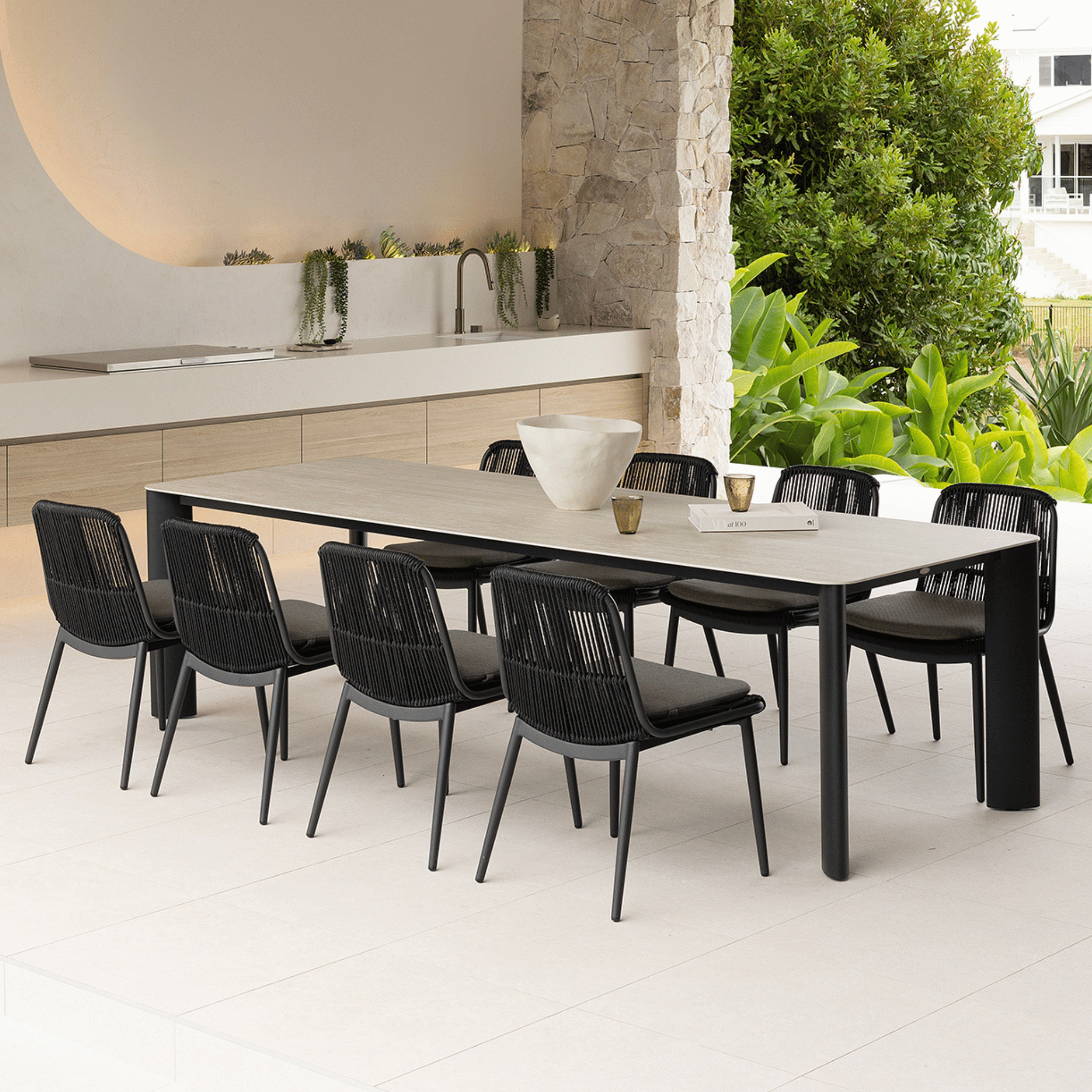 Black outdoor dining table with creamy stone top with 8 aluminium and rope chairs to match