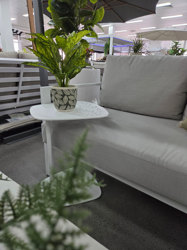 White outdoor sofa with a C-table and pot plant