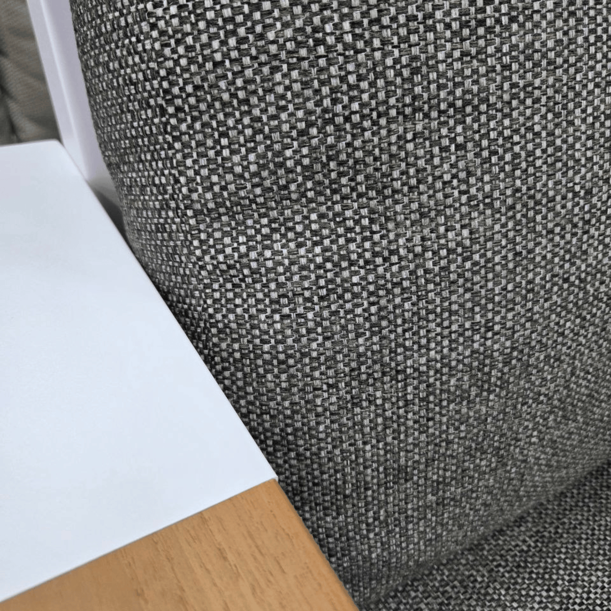 Close-up of the Aspen's charcoal texture fabric with a white frame and light wood armrests