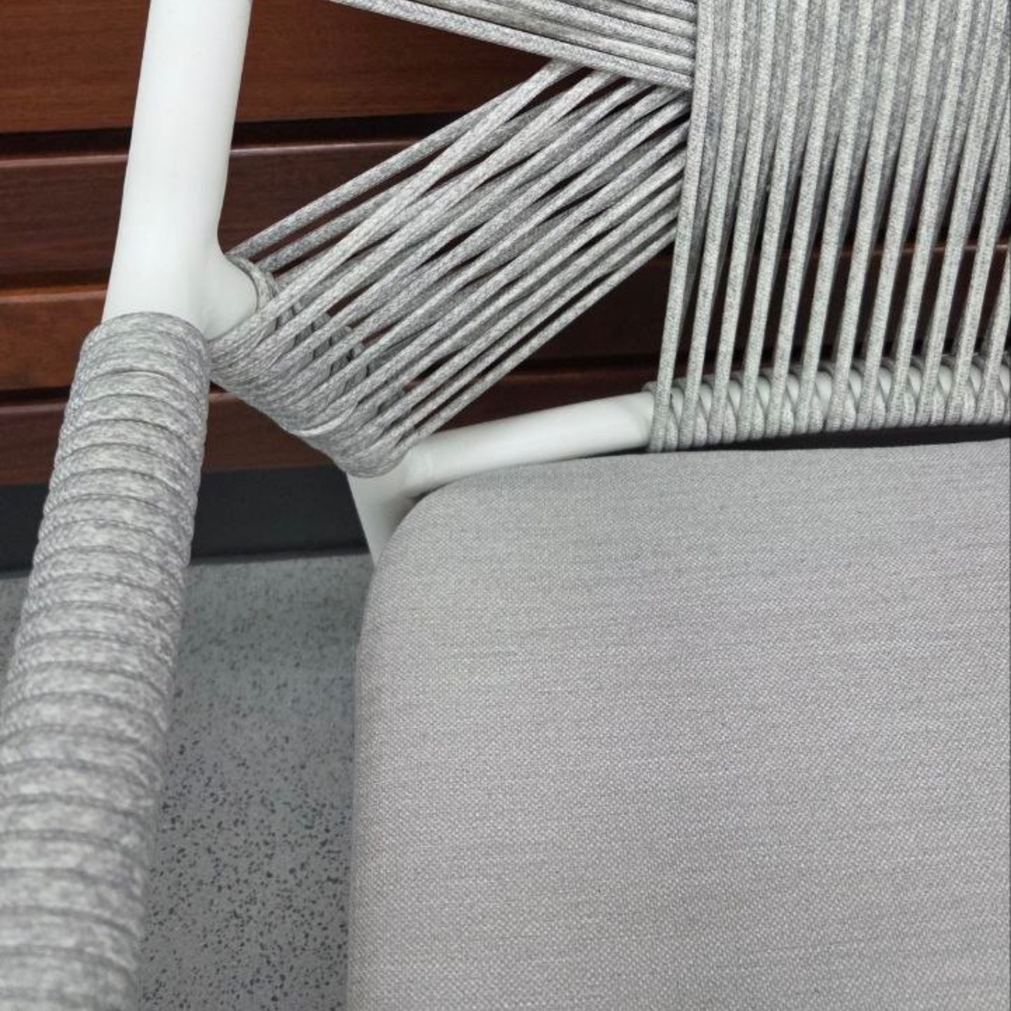 Close-up of a chair with grey woven backrest and white frame.