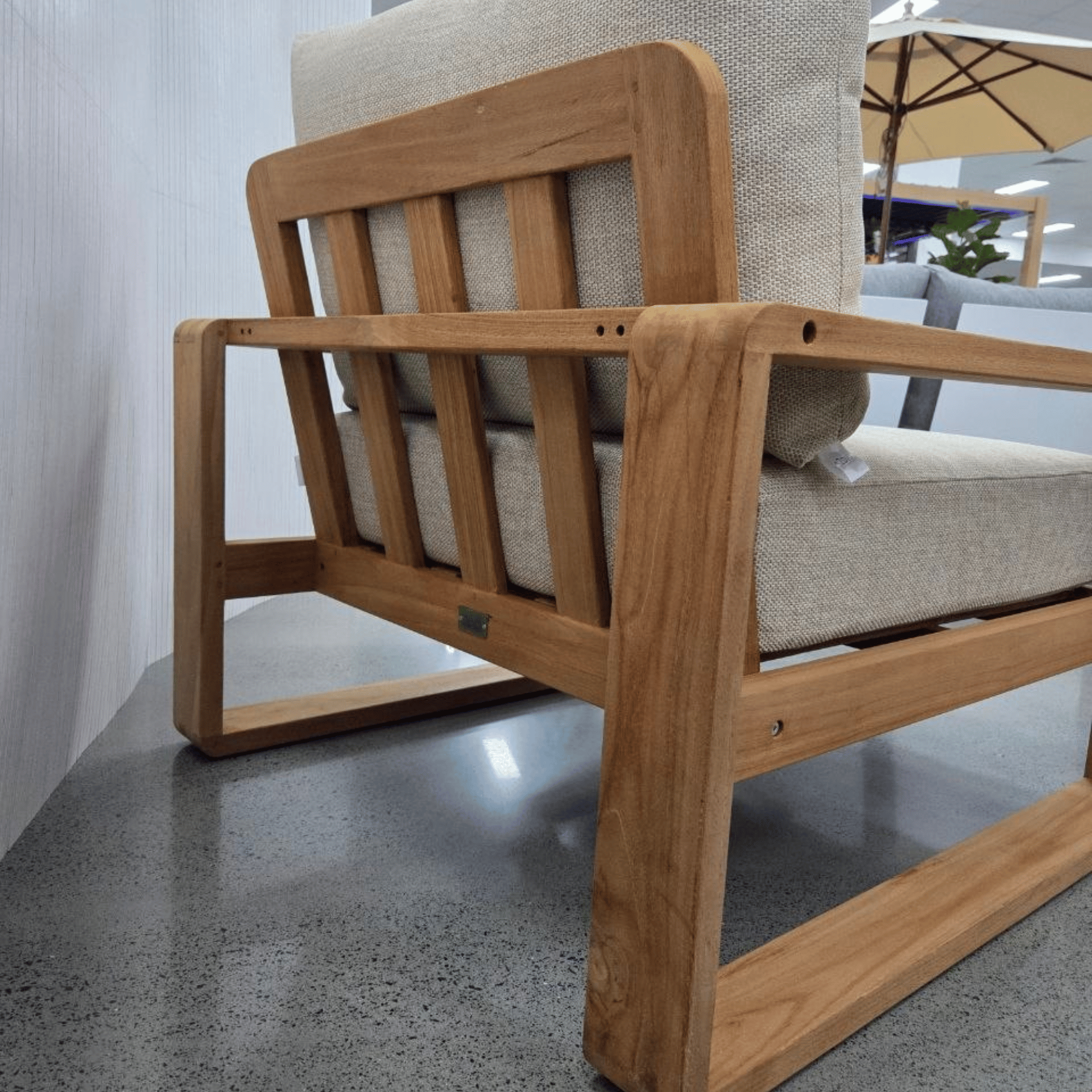 Back view of single teak Honolulu lounge chair with beige cushions