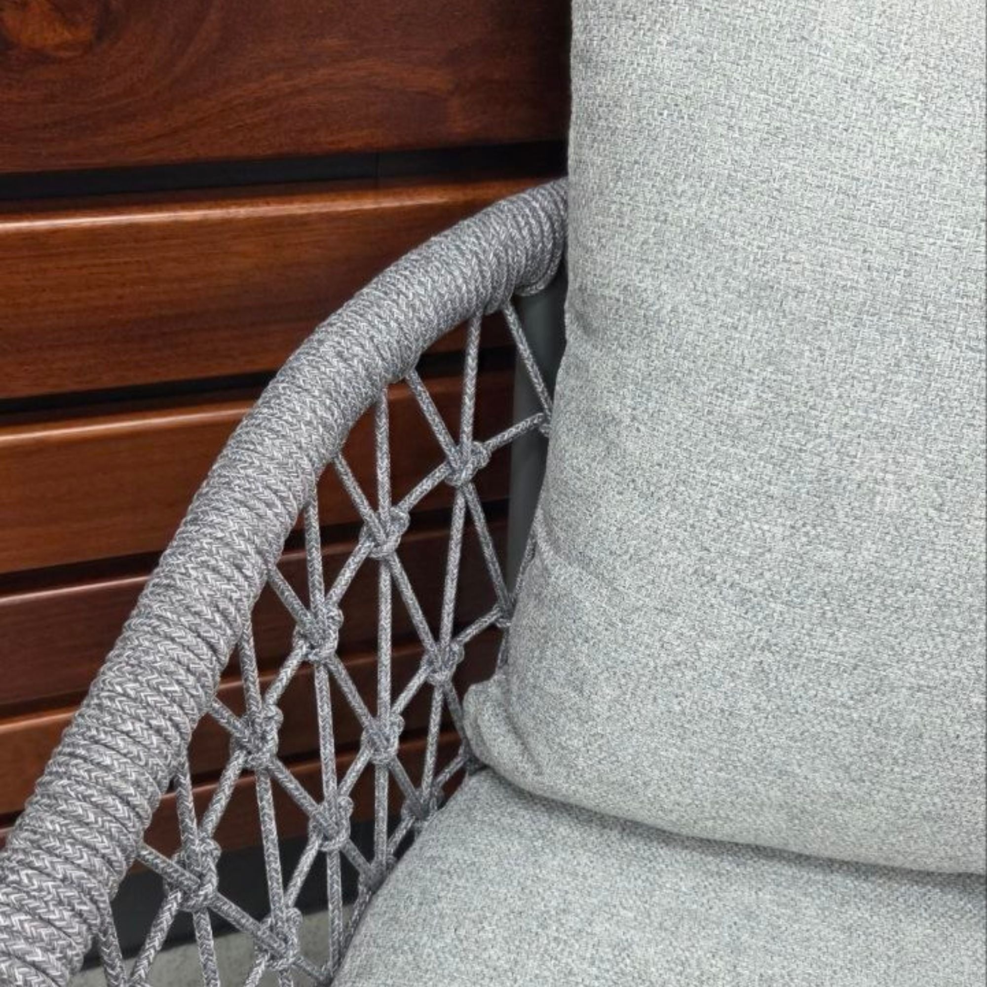 Close up of the weave and cushions Kinsley Dining Chair - Charcoal frame and grey rope weave with back and seat cushions, angled side view against a wooden wall