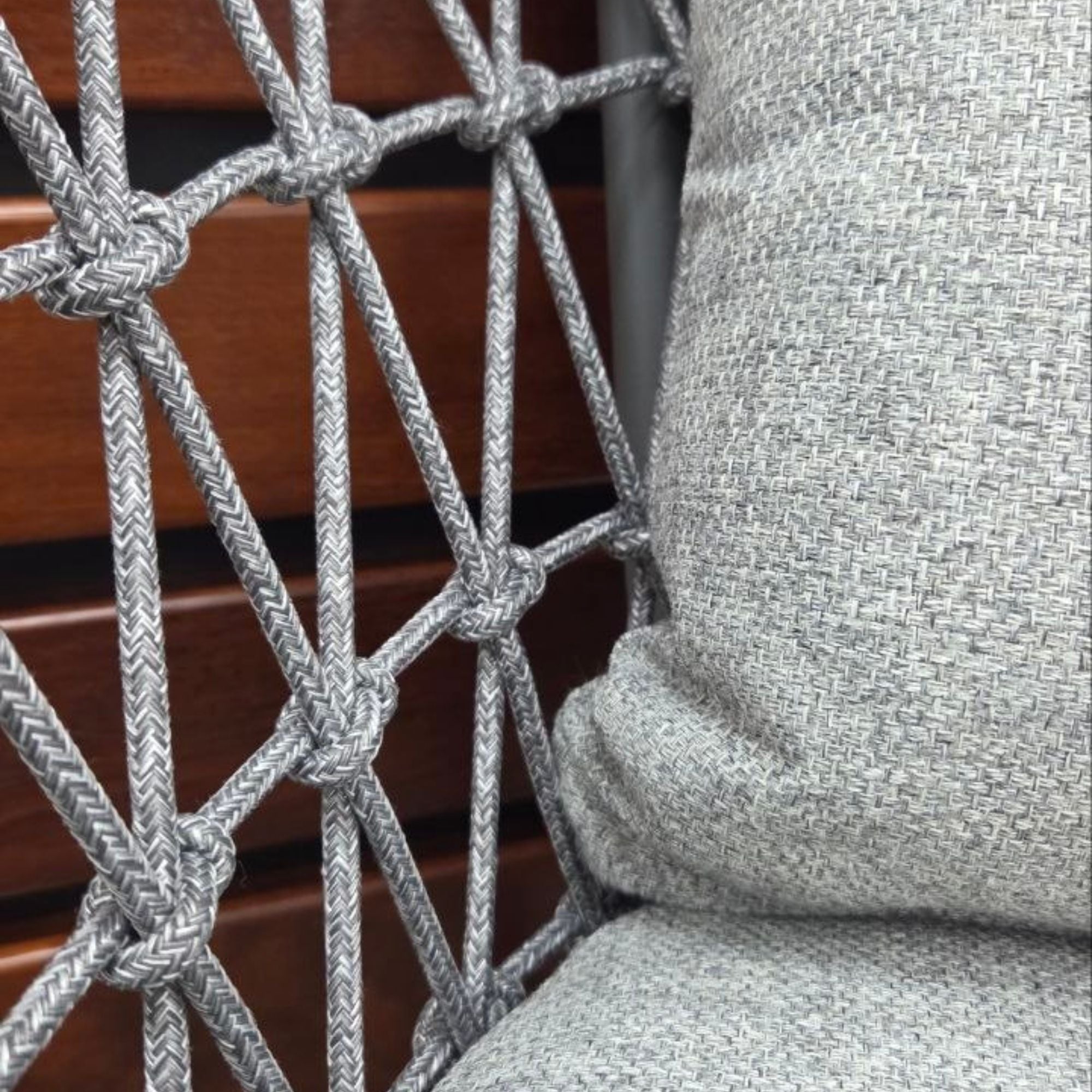 Intricate rope weave on the Kinsley Dining Chair - Charcoal frame and grey rope weave with back and seat cushions,  against a wooden wall