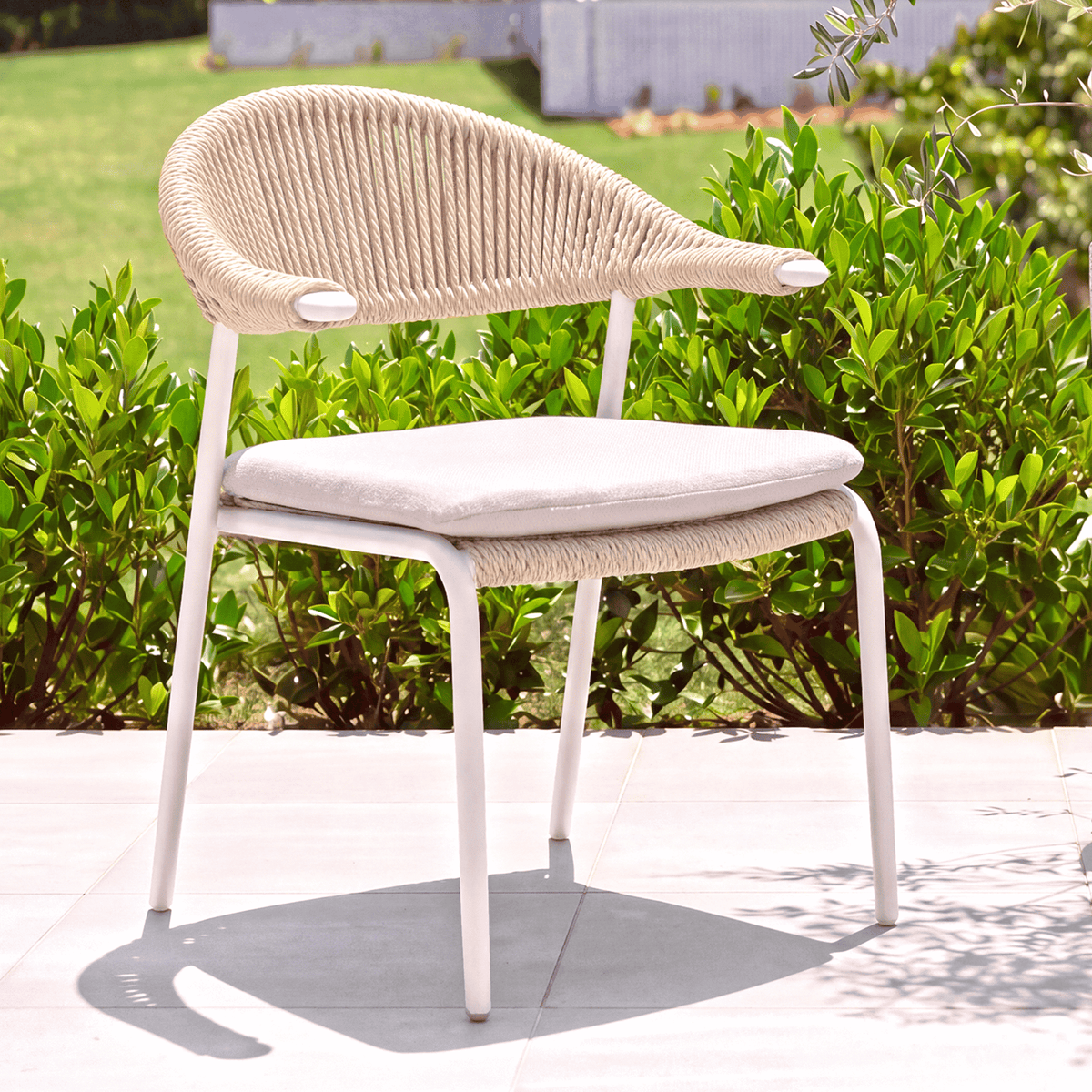 Mila Woven Dining Chair - White Beige Boucle on tiled floor and bushes in background