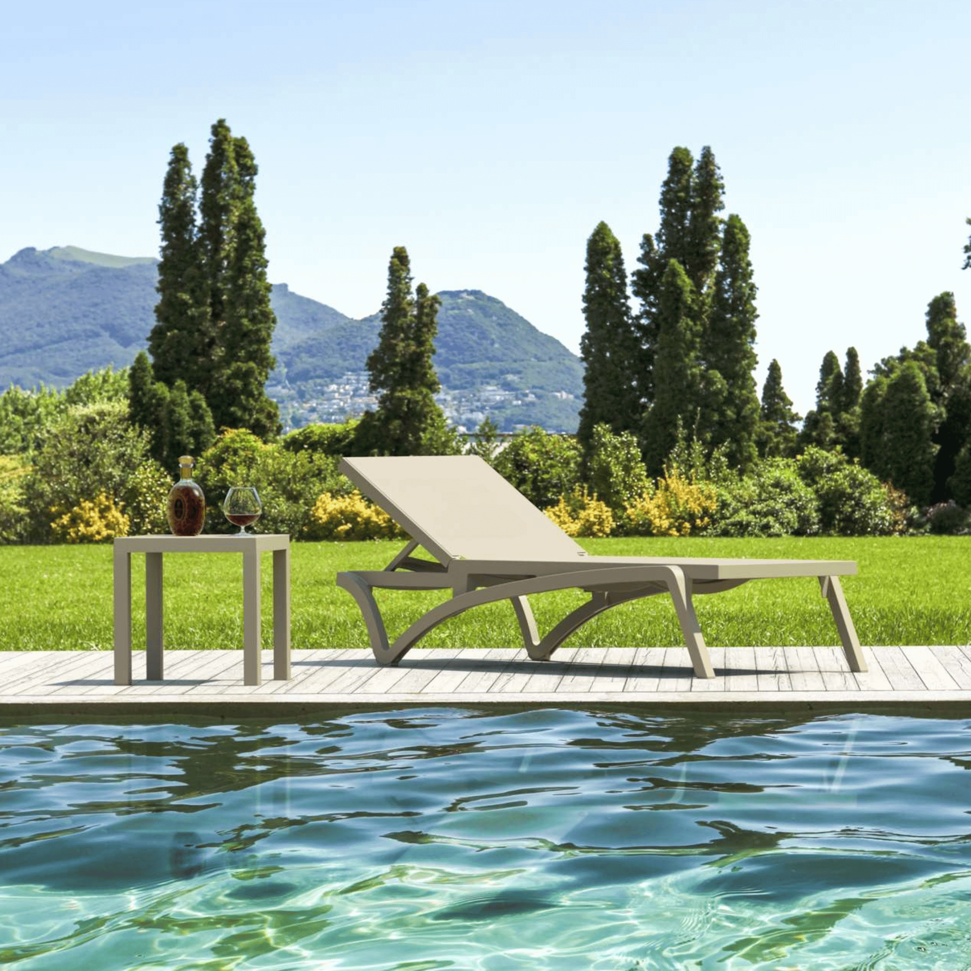 Siesta Pacific Sunlounge - Taupe - Commercial Grade with Ocean side table by a pool with mountains in the background